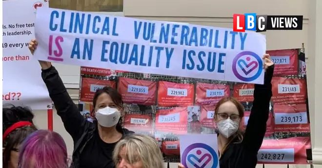 Campaigners wearing masks hold a banner reading "Clinical vulnerability is an equality issue".