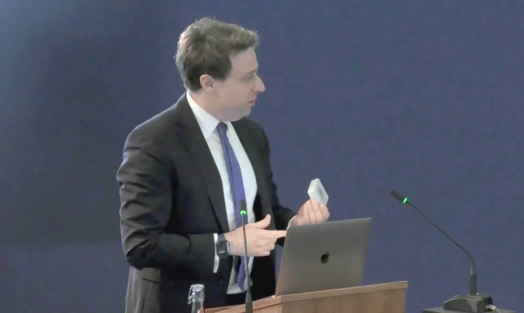 Adam Wagner KC, CVF’s barrister, holds up a CO₂ monitor to show the air quality at a UK Covid-19 Inquiry hearing.