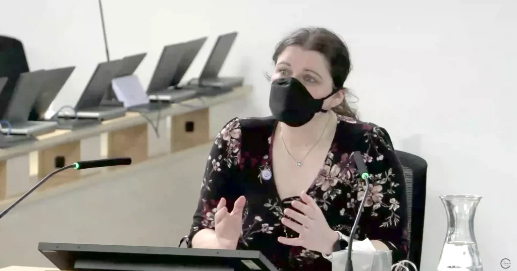 Lara Wong, wearing a black face mask, gives evidence for Clinically Vulnerable Families at the UK Covid-19 Inquiry, gesturing with both hands as she speaks.