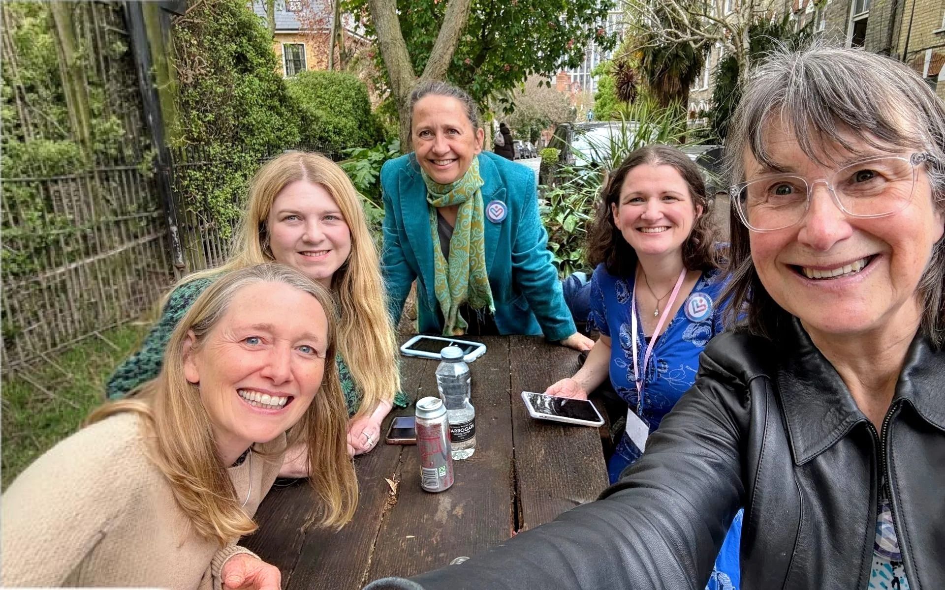 Five smiling members of the CVF team gathered around an outdoor table, two wearing CVF badges.