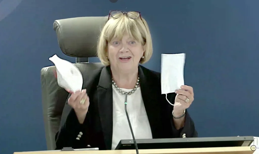 Baroness Hallett, Chair of the UK Covid-19 Inquiry, holds up a respirator mask in one hand and a surgical mask in the other.
